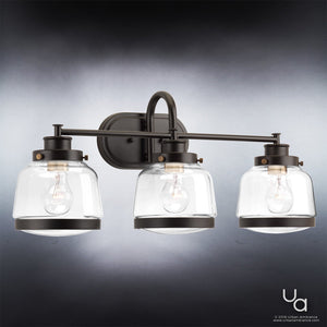 The Urban Ambiance UHP2539 Luxe Industrial Bathroom Vanity Light from the Nottingham Collection features three clear glass shades set on a sturdy Olde Bronze finished frame, mounted on a matching backplate and displayed against a gradient background. The fixture measures 11.25 inches in height and 26 inches in width, exemplifying industrial-inspired style.