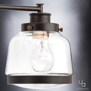 Close-up of the Urban Ambiance UHP2539 Luxe Industrial Bathroom Vanity Light from the Nottingham Collection, featuring an olde bronze finish, clear glass shade, and visible bulb design, mounted against a neutral background.