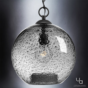 The UHP2580 Vintage Pendant from Urban Ambiance’s Birmingham Collection showcases a bubble-textured clear glass globe suspended by a metal chain in a sophisticated charcoal finish. Measuring 14″ high by 11-3/4″ wide, this artisan pendant features an exposed bulb design, infusing any space with vintage-inspired charm and distinctive lighting appeal.