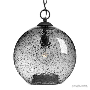 Illuminate your space with the Urban Ambiance UHP2580 Vintage Pendant from the Birmingham Collection, featuring a clear, textured artisan glass shade and a visible bulb inside, suspended by a black metal chain with a stylish charcoal finish for timeless vintage charm. Measures 14″H x 11-3/4″W.