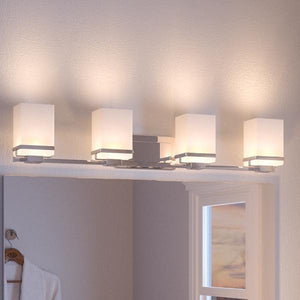 The UHP2605 Transitional Bathroom Vanity Light from Urban Ambiance’s Modena Collection features four etched opal glass square shades and a polished chrome finish, measuring 6.5″ high by 31.25″ wide—delivering a soft, even glow above your wall mirror for elegant and inviting modern bathroom lighting.