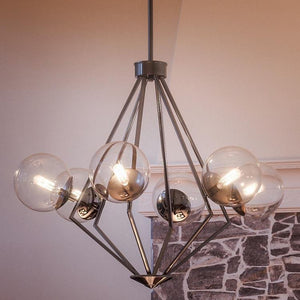 The Urban Ambiance UHP2624 Modern Chandelier from the Costa Mesa Collection, featuring a polished chrome finish and measuring 24-7/8″ x 34″, hangs above the stone fireplace.