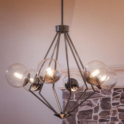 A Unique Modern Chandelier, 24-7/8" x 34", in a Polished Chrome Finish from the Costa Mesa Collection, featuring gorgeous glass globes suspended above a stone fireplace.