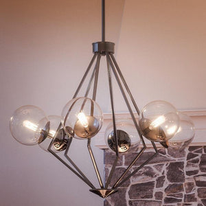 A Unique Modern Chandelier, 24-7/8" x 34", in a Polished Chrome Finish from the Costa Mesa Collection, featuring gorgeous glass globes suspended above a stone fireplace.