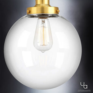The Urban Ambiance UHP2643 Vintage Pendant from the Glasgow Collection, featuring a clear glass globe and a native brass finish that highlights its visible filament bulb, elegantly showcases vintage modern lighting against a gray background.