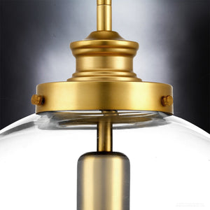Close-up of the Urban Ambiance UHP2645 Vintage Pendant from the Glasgow Collection, featuring a clear glass shade and metal hardware with a native brass finish, set against a dark gradient background; fixture measures 15″ high by 12″ wide.