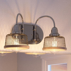 The Urban Ambiance UHP2720 Vintage Bathroom Vanity Light from the Eugene Collection features a brushed nickel finish and two mesh-covered bulbs in an industrial design, wall-mounted above a mirror on a white textured wall. Dimensions: 8.375″H x 15″W.