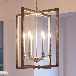 The Urban Ambiance UHP2741 Modern Farmhouse Chandelier from the Brighton Collection, featuring a galvanized steel finish and measuring 28-3/4 inches high by 26 inches wide, hangs from the ceiling in a softly lit room with its six candle-style bulbs.