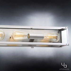 A close-up of the Urban Ambiance UHP2752 Luxe Industrial Electric Bath Fixture from the Messina Collection, measuring 4-1/2 inches high by 30 inches wide with a stainless steel finish, shows two exposed vintage-style filament bulbs mounted on a wall, emphasizing the sophisticated modern design of this bath light.