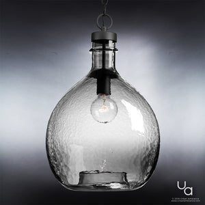 The Urban Ambiance UHP2770 Modern Farmhouse Pendant from the Hobart Collection features a clear, textured glass shade in a rounded bottle silhouette, suspended by a chain. Measuring 20-3/8″ high by 13″ wide and finished in charcoal, this artisanal fixture elegantly displays a visible bulb against a gray gradient background.