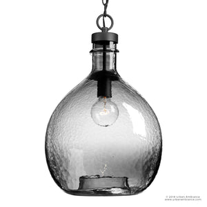 The UHP2770 Modern Farmhouse Pendant from Urban Ambiance’s Hobart Collection features a clear textured glass shade with a charcoal-finished metal fixture and chain, showcasing an exposed bulb for artisanal lighting style—perfect for enhancing any space.
