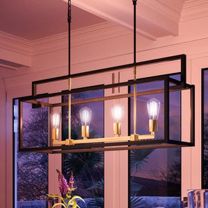 The UHP2801 Modern Farmhouse Chandelier from Urban Ambiance’s Cordoba Collection, featuring a charcoal finish and measuring 17-1/4″ x 40-7/8″, hangs from the ceiling in a modern room with large windows at dusk, adding a touch of vintage-inspired lighting to the space.