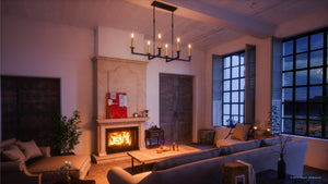 A modern living room featuring a lit fireplace, two sofas, a coffee table, large windows, wall art above the mantel, and a striking Urban Ambiance UHP2803 Modern Farmhouse Chandelier from the Cordoba Collection (15-5/8″ x 40″, Charcoal Finish) suspended from the ceiling.