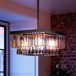 A unique and gorgeous lighting fixture, the UHP2884 Cosmopolitan Chandelier from the Lille Collection by Urban Ambiance, hangs over a brick wall in an Olde Bronze Finish.
