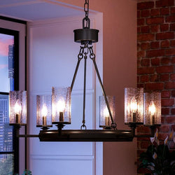 A luxury lighting fixture, UHP2891 Rustic Chandelier in a charcoal finish, Livorno Collection by Urban Ambiance, illuminates a room with a brick wall.