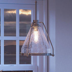 A UHP2992 Industrial Pendant Light, 13" x 13", Polished Nickel Finish, Rochdale Collection from Urban Ambiance hangs as a gorgeous lighting fixture over a window in a living