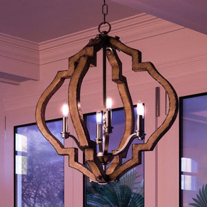 The UHP3030 Rustic Chandelier from Urban Ambiance’s Wycombe Collection features a wooden geometric design with an Olde Iron Finish and four exposed bulbs, suspended from the ceiling in a room adorned with large windows and crown molding.