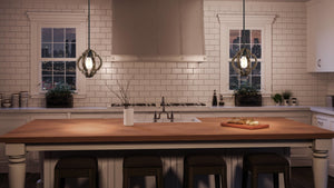A modern kitchen features white subway tile walls, a wooden island countertop surrounded by four stools, and is illuminated by the Urban Ambiance UHP3032 Rustic Pendant Light from the Wycombe Collection (11″ x 10″, Olde Iron Finish) hanging above. A cutting board with bread rests on the island, while two windows showcase a nighttime city view.