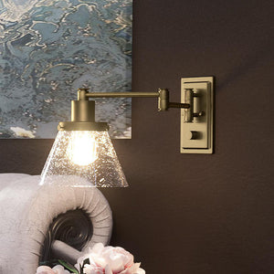 A room with a UHP3302 Traditional Wall Light, 9.625"H x 8"W, Olde Brass Finish lighting fixture and a painting on the wall.