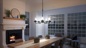 A dining room with a unique UHP3781 French Country Chandelier from Urban Ambiance and a fireplace.
