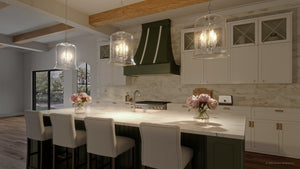 A unique pendant lamp with a brushed nickel finish and green counter tops in a rendering of a kitchen.