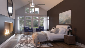 A modern bedroom with a fireplace, armchairs by large windows, a bed adorned with pillows and blankets, and a rug on wooden floors features the UHP9012 Urban Loft Indoor or Outdoor Ceiling Fan from the Mendocino Collection by Urban Ambiance. Measuring 16″ high by 56″ wide in matte white, this stylish ceiling fan perfectly complements the room’s inviting ambiance.