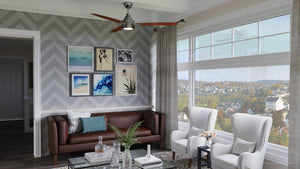 Modern living room featuring a brown leather sofa, two white armchairs, framed art on a patterned wall, large windows, and the Urban Ambiance UHP9041 Mid Century Modern Indoor Ceiling Fan from the Tybee Collection in brushed nickel (13.1″H x 60″W).
