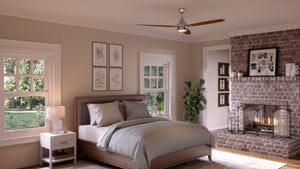 A bedroom featuring a bed with gray bedding, a nightstand, wall art, shelves, a brick fireplace, and large windows overlooking greenery outside is illuminated by the UHP9043 Mid Century Modern Indoor Ceiling Fan from Urban Ambiance’s Tybee Collection (13.1″H x 60″W, Polished Chrome).