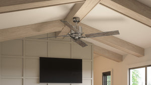 An Urban Ambiance UHP9061 Urban Loft Indoor Ceiling Fan from the Amelia Collection, featuring four wooden reversible blades and an aged nickel metal center, is mounted on a vaulted ceiling above a wall-mounted flat-screen TV in a modern living room.
