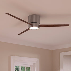 The UHP9070 Modern Indoor Ceiling Fan from the Camden Collection by Urban Ambiance, featuring three wooden blades and an integrated LED light fixture in a brushed nickel finish (9.9″H x 56″W), is installed on a beige ceiling above a window.