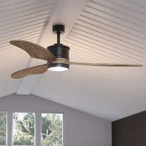 The UHP9090 Modern Indoor Ceiling Fan from the Urban Ambiance Lewes Collection features solid wood blades and an integrated LED light fixture, shown mounted on a white vaulted ceiling above windows. The fan measures 15.5 inches high by 60 inches wide and comes in a charcoal finish.