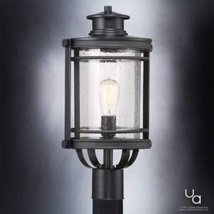 The Urban Ambiance UQL1010 Mid-Century Modern Outdoor Post Light from the Cannes Collection features a black silk finish, clear seeded glass housing, and an exposed filament bulb in a vintage-inspired lantern design, measuring 19.5 inches high by 10.5 inches wide and showcased against a neutral gradient background.