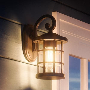 An Urban Ambiance UQL1040 Craftsman Outdoor Wall Light (11"H x 6"W, Natural Black, Vienna Collection) with marine-grade construction is illuminated beside a white-framed window on a house exterior at dusk.
