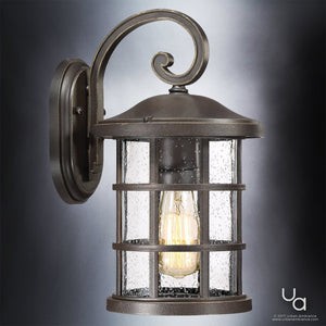 Experience the Urban Ambiance UQL1043 Craftsman Outdoor Wall Light from the Vienna Collection, featuring a Parisian Bronze finish and marine-grade construction. This 14.25″H x 8″W sconce showcases clear seedy glass panels, a visible vintage-style bulb, and a gracefully curved arm mounted on a round backplate—an elegant tribute to classic Craftsman design.