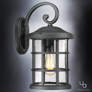 The Urban Ambiance UQL1044 Vienna Collection Craftsman Outdoor Wall Light features a natural black finish, curved arm, clear seeded glass with raindrop texture, and marine-grade construction for lasting beauty. 17.75