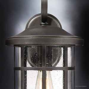 Close-up of the Urban Ambiance UQL1045 Craftsman Outdoor Wall Light from the Vienna Collection, shown in a Parisian Bronze finish with clear seeded glass panels featuring a raindrop texture. The 17.75″ high by 10″ wide marine-grade sconce is mounted on a wall, with light bulbs visible inside.