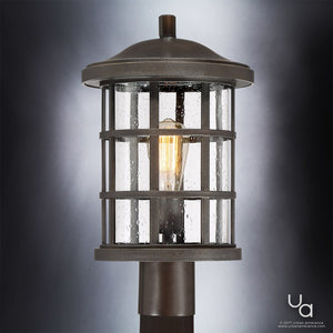 Showcased against a gradient background, the Urban Ambiance UQL1047 Craftsman Outdoor Post Light from the Vienna Collection highlights its marine-grade construction and elegant Parisian Bronze finish. This 17.25″ high by 10″ wide outdoor lantern features a cylindrical, glass-enclosed design with a visible glowing bulb inside, blending vintage charm with durability.