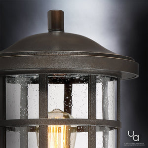 Close-up of the Urban Ambiance UQL1047 Craftsman Outdoor Post Light from the Vienna Collection, featuring marine-grade construction and a lit bulb visible through rain-speckled glass panels, finished in elegant Parisian Bronze and set against a neutral gray backdrop.