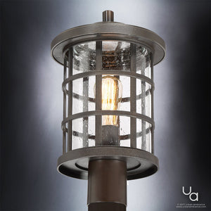 Introducing the Urban Ambiance UQL1047 Craftsman Outdoor Post Light from the Vienna Collection, this marine-grade fixture features a cylindrical silhouette with a metal cage and glass panels adorned with a water droplet texture. Finished in Parisian Bronze and measuring 17.25″ high by 10″ wide, it showcases a visible bulb inside for classic vintage lantern appeal.
