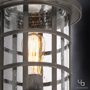 Close-up of the Urban Ambiance UQL1047 Craftsman Outdoor Post Light from the Vienna Collection, showcasing its Parisian Bronze finish, marine-grade construction, and metal grid frame with water droplets on the glass and a lit bulb inside.