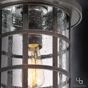 Close-up of the Urban Ambiance UQL1049 Craftsman Outdoor Pendant Light from the Vienna Collection, featuring a Parisian Bronze metal frame and clear, seeded glass that displays water droplets; measures 15.5″ high by 10″ wide with marine-grade construction.