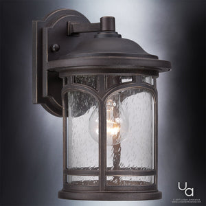 Illuminate your exterior spaces with the Urban Ambiance UQL1101 Rustic Outdoor Wall Light from the Sydney Collection. Featuring a round, seeded glass shade and a Parisian Bronze-finished dark metal frame that reveals a visible bulb, this 11″H x 7″W wall-mounted sconce offers marine-grade, weather-resistant construction for timeless charm and lasting durability outdoors.