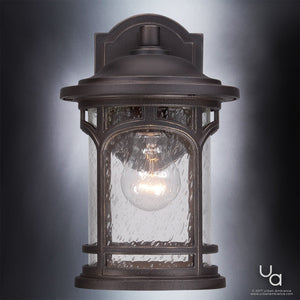 The Urban Ambiance UQL1101 Rustic Outdoor Wall Light from the Sydney Collection features a Parisian Bronze finish, marine-grade construction, a clear seeded glass shade with a visible bulb, and is stylishly weather-resistant—shown mounted against a gradient gray background.