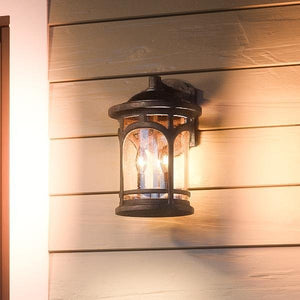 An Urban Ambiance UQL1103 Rustic Outdoor Wall Light from the Sydney Collection, featuring a Parisian Bronze finish and marine-grade construction, is mounted on beige horizontal siding.