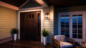 At dusk, a contemporary porch showcases the Urban Ambiance UQL1103 Rustic Outdoor Wall Light from the Sydney Collection. Finished in elegant Parisian Bronze, this 14.5″ x 9″ marine-grade fixture casts a soft glow through its seeded glass beside sliding glass doors. Paired with a dark wooden door, two potted plants, and a cushioned chair, the sconce adds warmth and sophistication to the welcoming space.