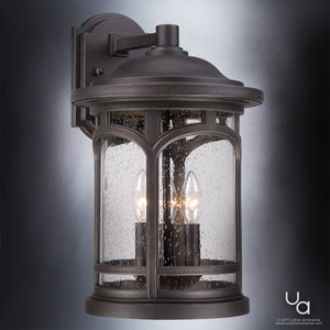 The UQL1105 Rustic Outdoor Wall Light by Urban Ambiance from the Sydney Collection features a Parisian Bronze finish and marine-grade construction. Measuring 17.75″ high by 11″ wide, this elegant sconce showcases seeded glass panels with a raindrop texture and houses two candle-style bulbs, making it an ideal statement piece for your outdoor space.
