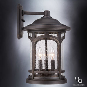 The Urban Ambiance UQL1105 Rustic Outdoor Wall Light from the Sydney Collection features a sophisticated Parisian Bronze finish, marine-grade construction, and measures 17.75 inches high by 11 inches wide. This elegant wall sconce showcases clear seeded glass panels and two exposed candle-style bulbs for striking outdoor illumination.
