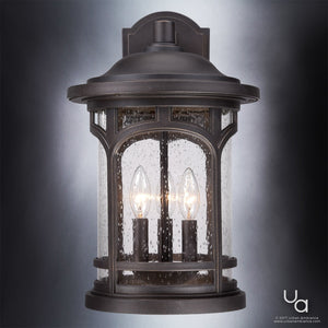 Urban Ambiance UQL1105 Rustic Outdoor Wall Light from the Sydney Collection, measuring 17.75″ high by 11″ wide, showcases a Parisian Bronze finish and clear seeded glass with two candle-style bulbs, set against a gray gradient background.