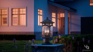 The Urban Ambiance UQL1107 Rustic Outdoor Post Light from the Sydney Collection, featuring a marine-grade Parisian Bronze finish and seeded glass, stands on a pedestal in the garden at dusk, complementing the modern house and blooming flowers visible in the background.