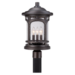 The Urban Ambiance UQL1107 Rustic Outdoor Post Light from the Sydney Collection features a Parisian Bronze finish, marine-grade construction, and three candle-style lights encased in clear seeded glass panels with a delicate texture. Measuring 19 inches high by 11 inches wide, it’s designed for stylish outdoor illumination.